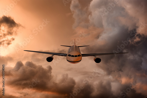 Jet Airliner flying through beautiful and dramatic sunset stormy and cloudy sky.
