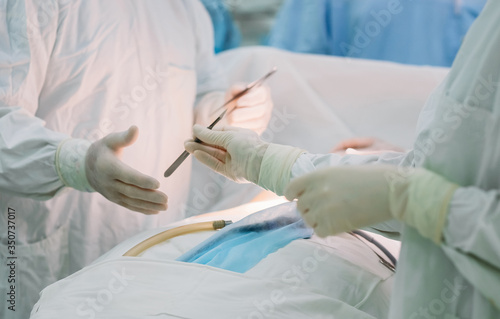 Nurse hands scalpel to surgeon during surgery 