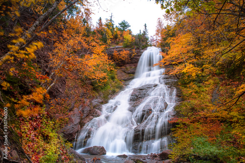 Gushing water fall in an autumn forest landscape with dense trees, Cape Breton. Beulach Ban Falls, Autumn waterfall view. 