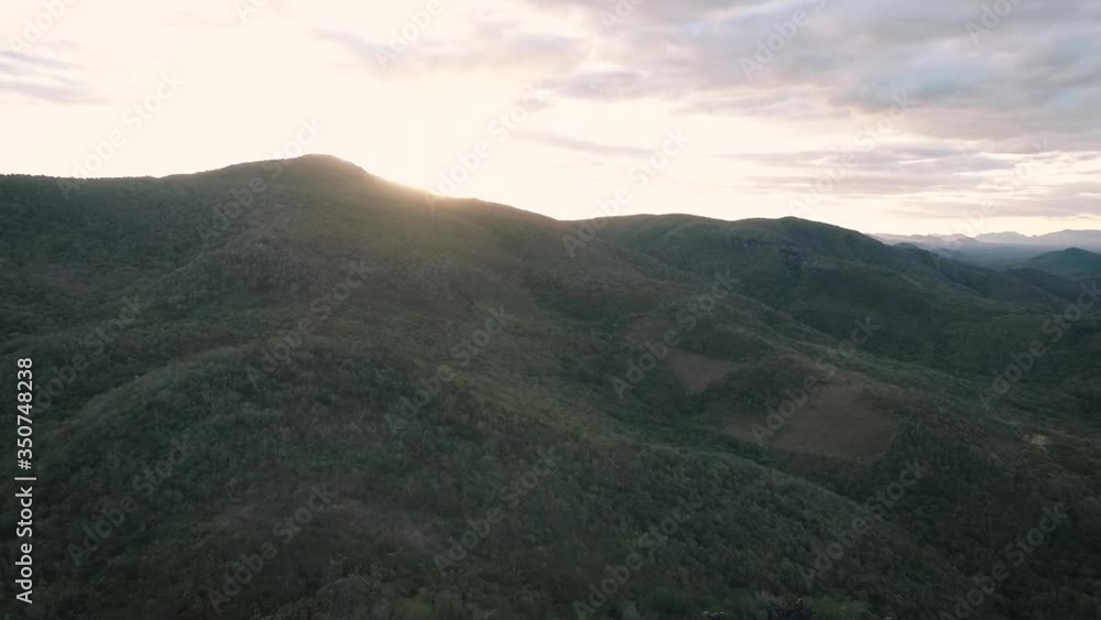 Sunset behind a large mountain with lush green vegetation, Drone approach movement, Echologic Park Furna dos Ossos, Canindé, Ceará, Brazil Sunset behind a large mountain with lush green vegetation, Drone approach movement, Echologic Park Furna dos Ossos, Canindé, Ceará, Brazil