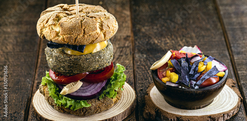 vegan meal, meatless hamburger, gluten free, made with different vegetables and proteins. Brown bread on gourmet hamburger, rustic background.