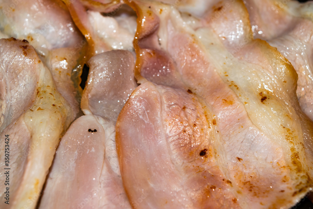Fried slices of raw bacon. Close up. Fried slices of raw bacon. Close up.