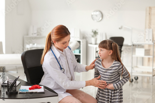 Gastroenterologist examining little girl in clinic