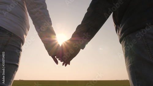 loving couple holding hands at sunset. Extend your hand to friend. sun's rays shine through your fingers. Love, Happiness and Friendship. Hands of man and woman at sunset. sunny glare through palms.
