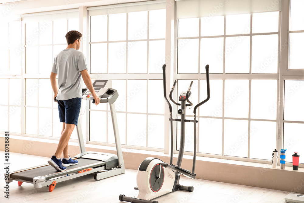 Young man training on treadmill in gym