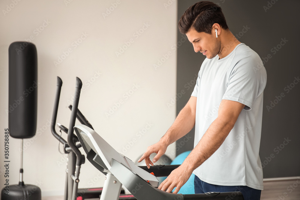 Young man training on treadmill in gym Young man training on treadmill in gym