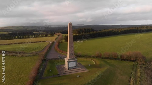 Orbiting point of interest aerial drone shot of Knockagh World War Monument during sunset showing surrounding fields photo