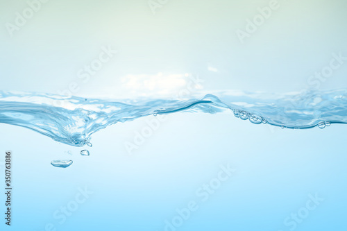 Water splash on blue background. Aqua flowing in waves and creating bubbles. Drops on the water surface feel fresh and clean.
