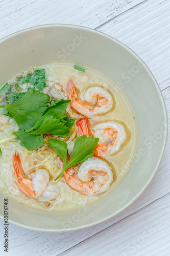 Thai rice soup with shrimp on bowl with white wood background