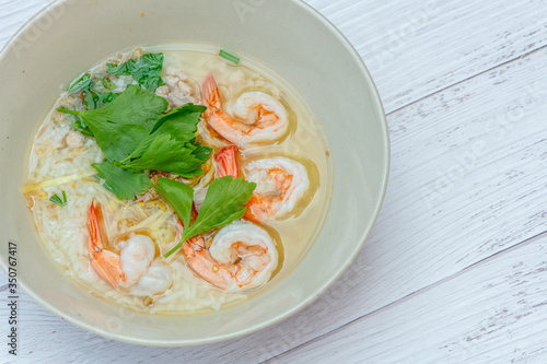 Thai rice soup with shrimp on bowl with white wood background