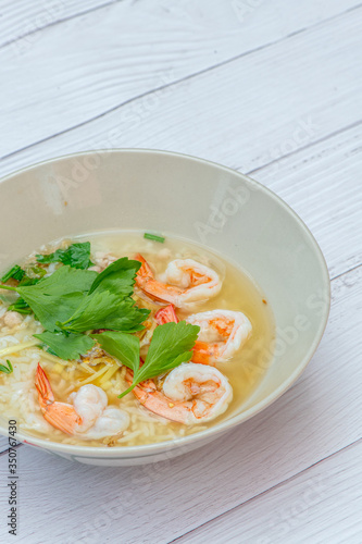 Thai rice soup with shrimp on bowl with white wood background