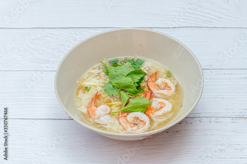 Thai rice soup with shrimp on bowl with white wood background