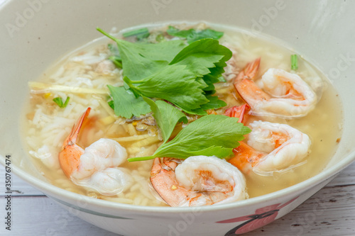 Thai rice soup with shrimp on bowl with white wood background