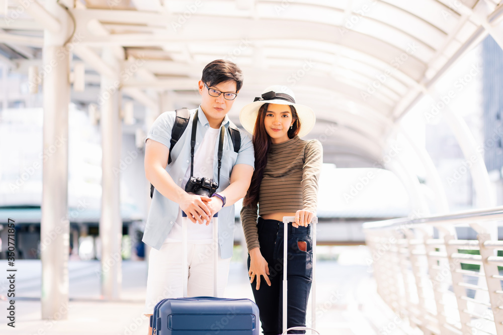 Thai men and women wear casual clothes. They are grabbing the baggage cart and looking at the camera in the concept of tourists who are going to travel on a summer holiday.