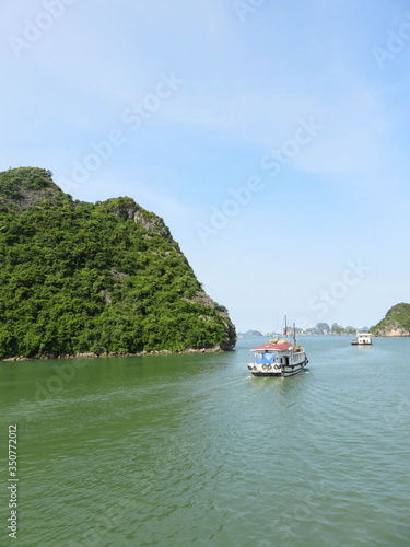 Boats on a cruise in Halong Bay, Vietnam. Rocks in the background and blue sky. © Chasing that horizon