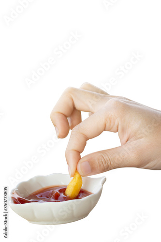 Hand holding french fries dipped in tomato sauce in a paper cup on a white background. French Fries highly popular in America. Is a diet that is high in fat unhealthy.