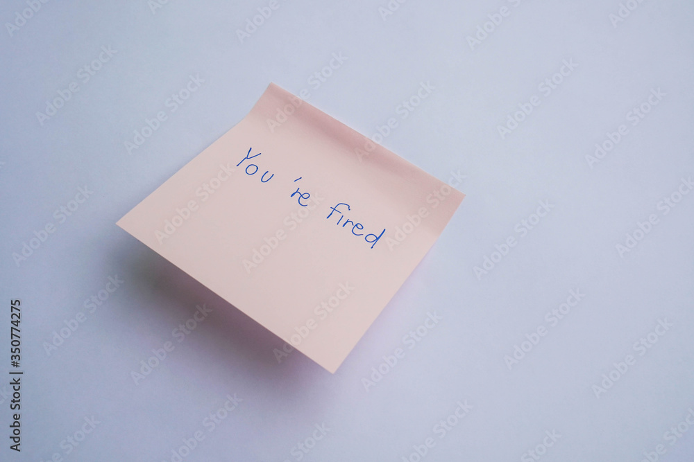 business concept of you are fired from the company handwritten on sticky note business concept of you are fired from the company handwritten on sticky note