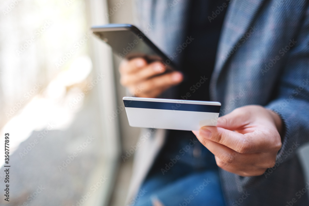 Closeup image of a woman using credit card for purchasing and shopping online on mobile phone Closeup image of a woman using credit card for purchasing and shopping online on mobile phone