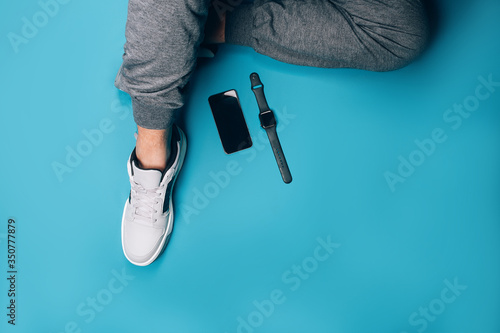 Stylish gray sneakers on blue background, stylish smart watches in black on blue background, healthy lifestyle, diet, black smart phone