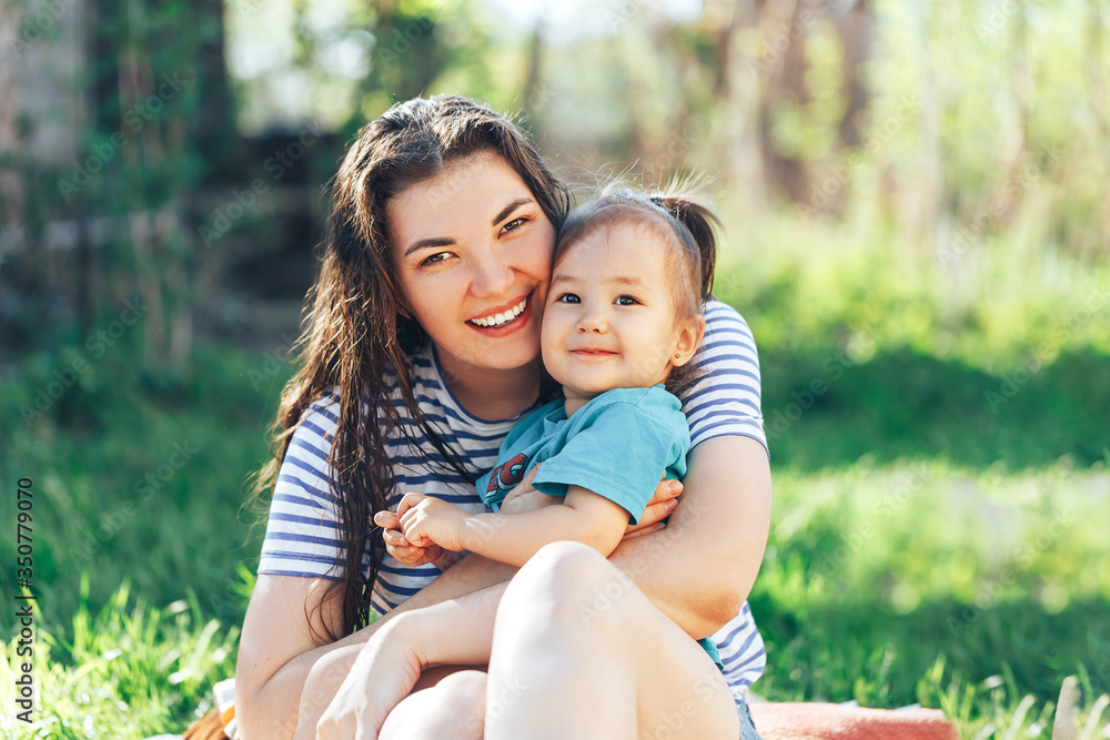 Young beautiful mother with daughter sit on an open-air lawn on a sunny day. Young beautiful mother with daughter sit on an open-air lawn on a sunny day.