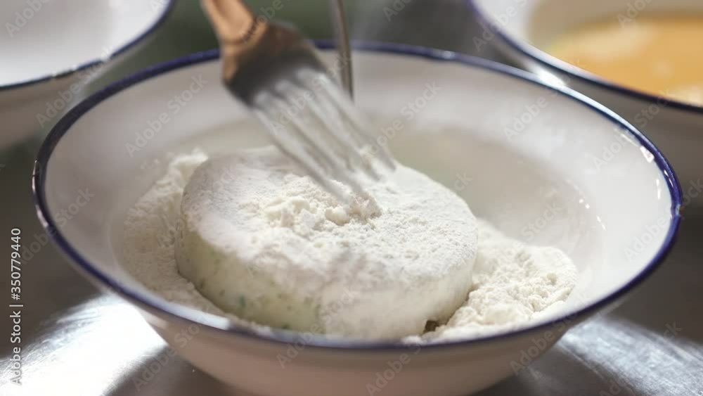 Someone making a healthy cod or stockfish patty. Hands with gloves on the fresh fish put into the flour, preparing to fry it. Someone making a healthy cod or stockfish patty. Hands with gloves on the fresh fish put into the flour, preparing to fry it.