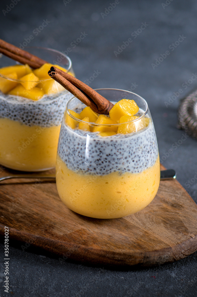 Chia pudding with mango sauce and fresh fruits on dark background Chia pudding with mango sauce and fresh fruits on dark background