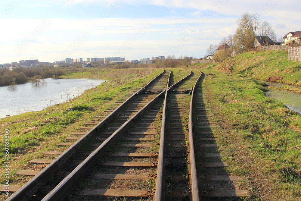 The railway stretching into the distance against the background of young green grass and trees in spring. The railway stretching into the distance against the background of young green grass and trees in spring.