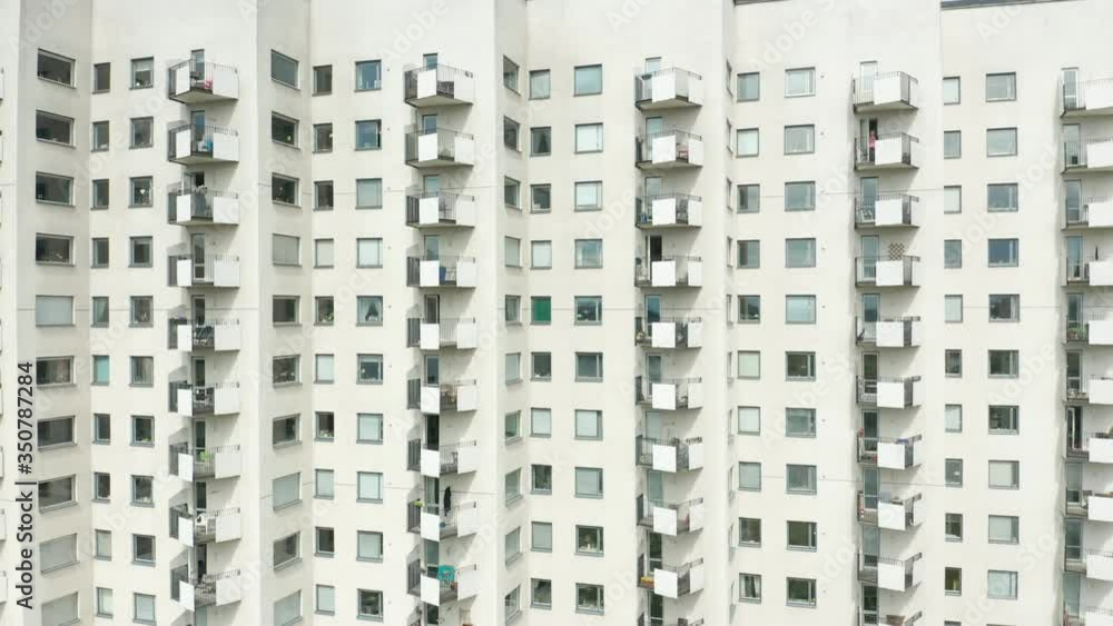 Exterior of a high rise multi story residential apartment building - white facade, windows & balconies. Establishing shot rising ascending aerial footage. Exterior of a high rise multi story residential apartment building - white facade, windows & balconies. Establishing shot rising ascending aerial footage.
