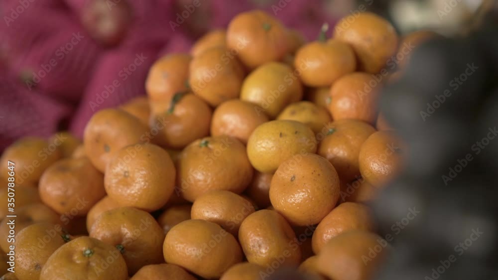 Lockdown shot of fresh orange fruits pile at market stall - Chiang Rai, Thailand Lockdown shot of fresh orange fruits pile at market stall - Chiang Rai, Thailand