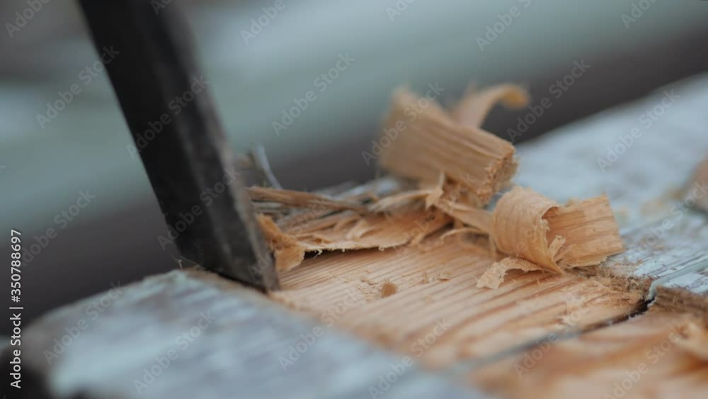 A novice carpenter works on wood with a chisel. Craftsman in the workshop A novice carpenter works on wood with a chisel. Craftsman in the workshop