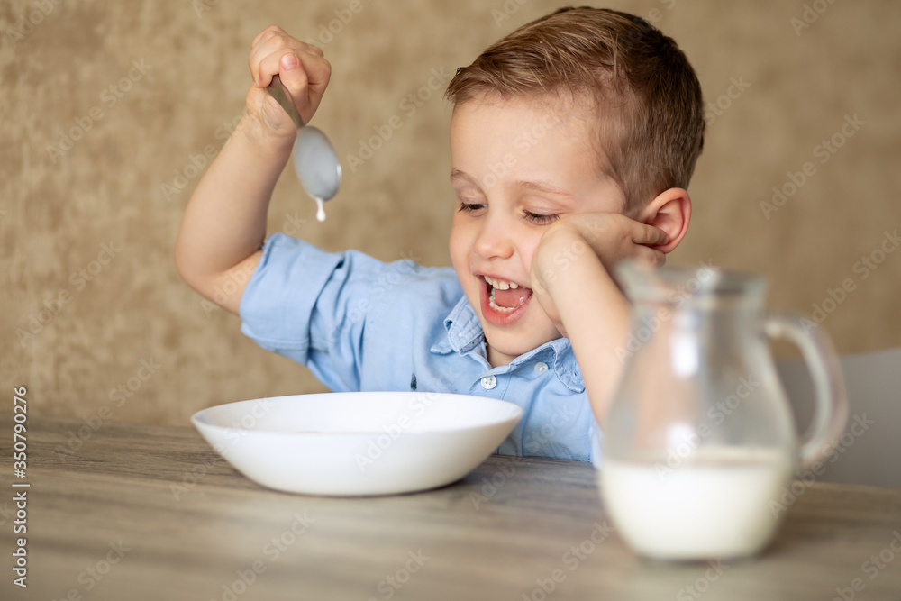 An adorable European baby eats porridge on his own. The boy does not like porridge. Plays with a spoon, pours milk. The child holds his head in his hand. An adorable European baby eats porridge on his own. The boy does not like porridge. Plays with a spoon, pours milk. The child holds his head in his hand.