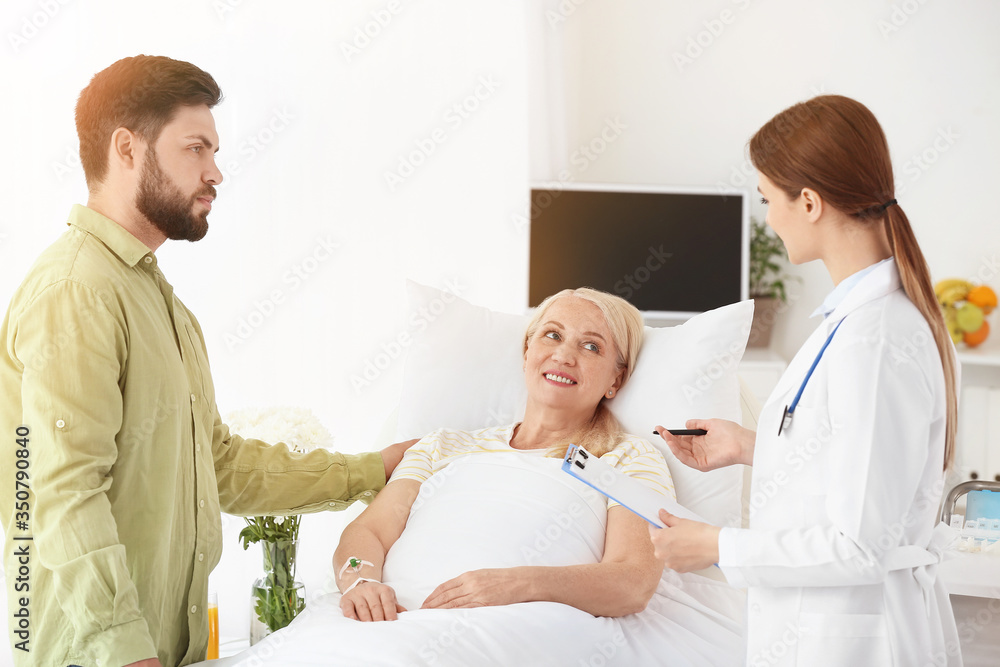 Mature woman with doctor and son in hospital room Mature woman with doctor and son in hospital room