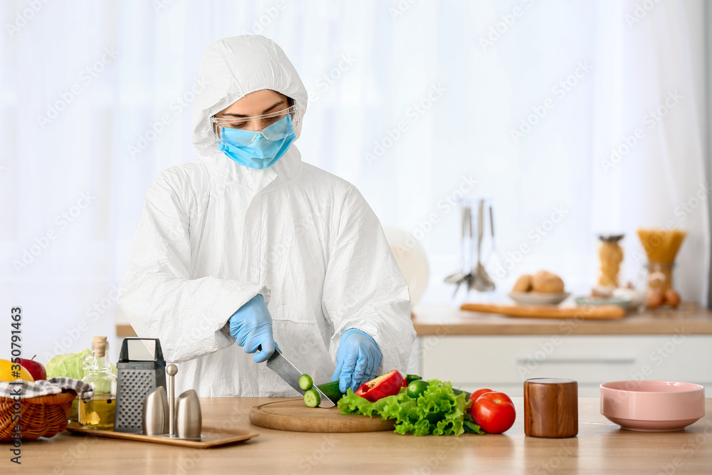 Woman in biohazard suit cooking in kitchen Woman in biohazard suit cooking in kitchen