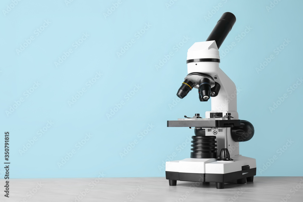 Modern microscope on table against color background Modern microscope on table against color background
