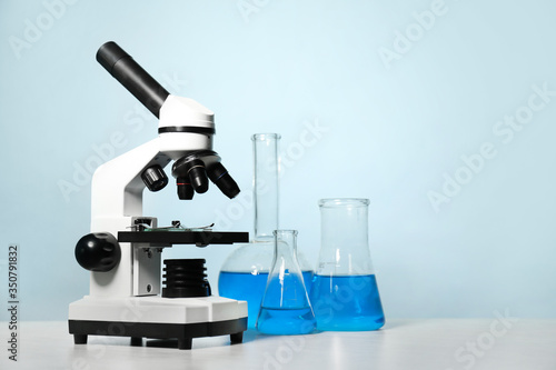 Modern microscope and laboratory glassware on table