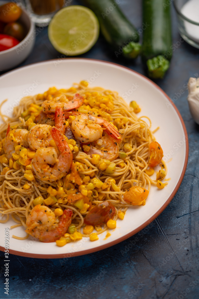 Fried vegetables, seafood shrimp with spaghetti on the background of vegetables and ingredients. On a blue texture Fried vegetables, seafood shrimp with spaghetti on the background of vegetables and ingredients. On a blue texture