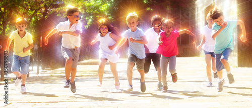 Group of joyful children running down the city street