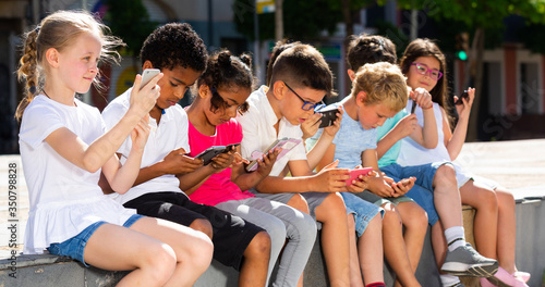 Eight kidsare chatting on their smartphone on walking