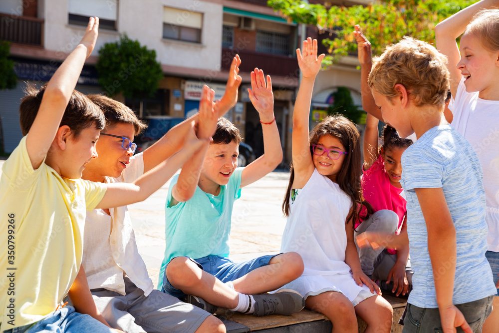 Obraz premium Group of positive children holding hands up and smiling together