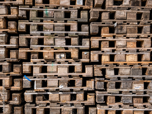 Stacked wooden pallets for industrial transportation. Piles of used pallets.
