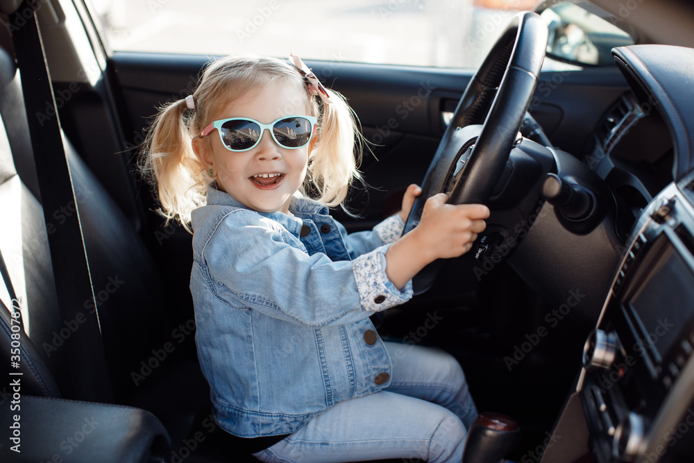 Foto Stock Cute little girl behind wheel of car.Baby girl sitting on
