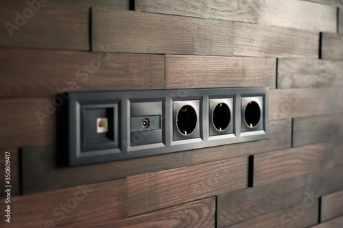 Electrical household switches and sockets close up. Minimalist interior design. Stylish bedroom and living room. Wooden bricks wall in a designer minimalist room. Wooden parquet room. Scandinavian sty