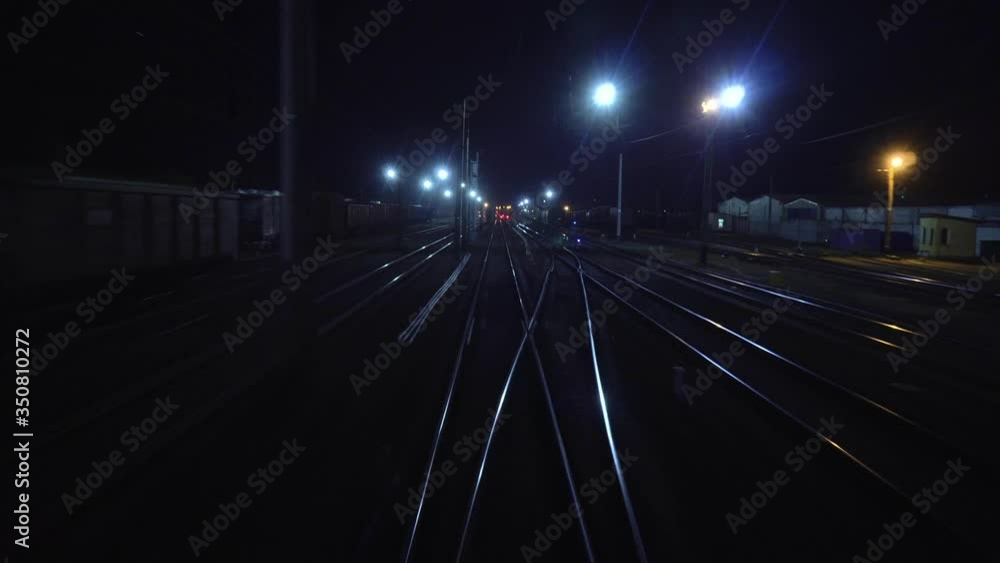 Railroad train passes through railway fork. View on rails from rear back window of last coach carriage at night in motion. Travel and tourism concept. Passenger train going outside of town Railroad train passes through railway fork. View on rails from rear back window of last coach carriage at night in motion. Travel and tourism concept. Passenger train going outside of town