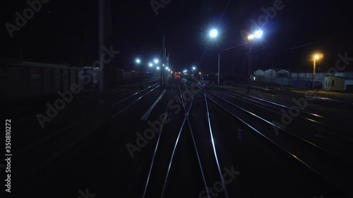 Railroad train passes through railway fork. View on rails from rear back window of last coach carriage at night in motion. Travel and tourism concept. Passenger train going outside of town photo