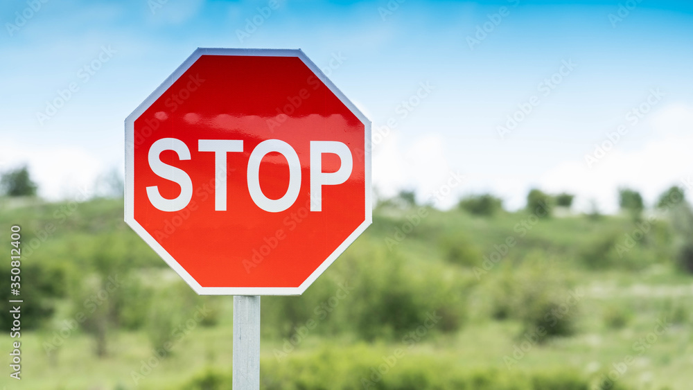 Red Stop Traffic Sign on Blue Sky Background and green field