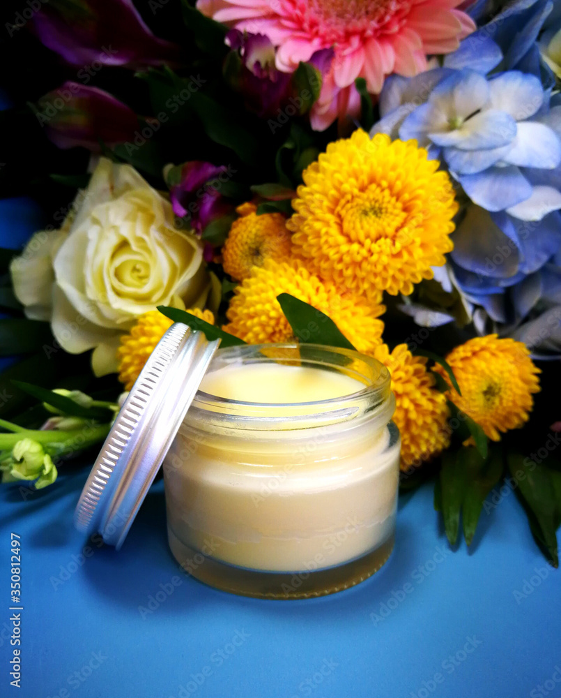 Cosmetic cream in a glass jar on a background of flowers. Branded packaging, the concept of bio organic natural cosmetics. Cosmetic cream in a glass jar on a background of flowers. Branded packaging, the concept of bio organic natural cosmetics.