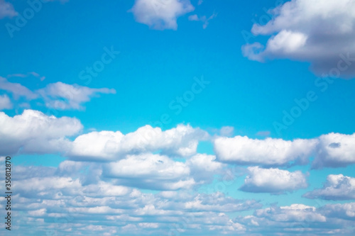 White fluffy clouds on a boundless blue sky. Nature background.