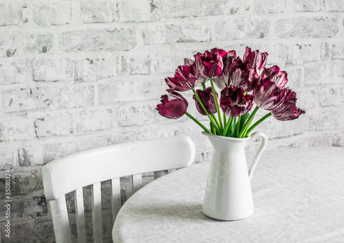 Fototapeta Naklejka Na Ścianę i Meble -  Bouquet of purple tulips on a table in a bright room. Cozy home concept, copy space