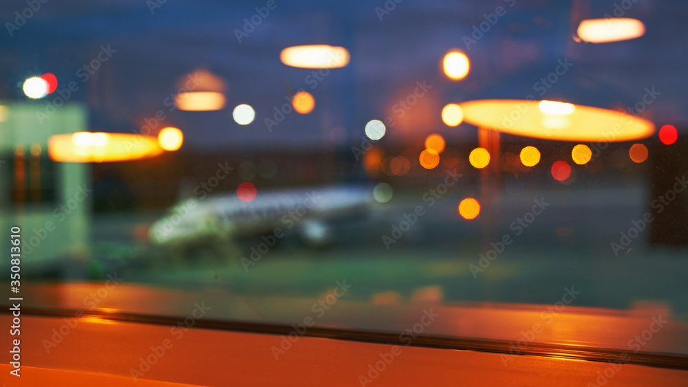 Blurred or defocused beautiful airport terminal early morning or night background with airplane, bokeh lights and glass reflections Blurred or defocused beautiful airport terminal early morning or night background with airplane, bokeh lights and glass reflections