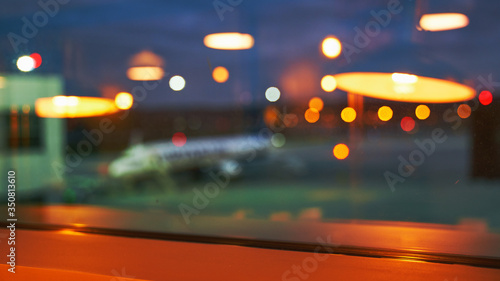 Blurred or defocused beautiful airport terminal early morning or night background with airplane, bokeh lights and glass reflections